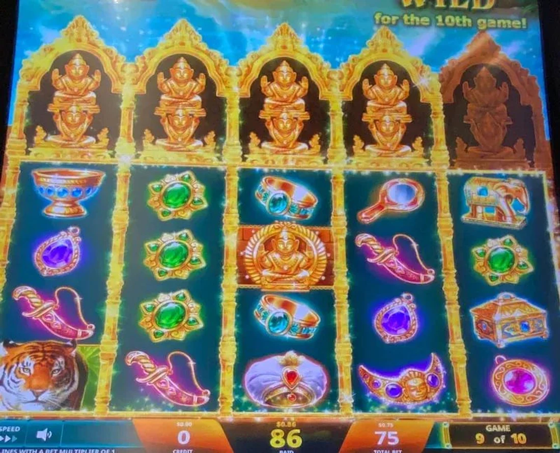 Read the buddha niches above the reels together with the GAME x of 10 counter — two buddhas stacked over a reel turns it fully wild for the 10th game. The niches plus the cycle position are the whole read.