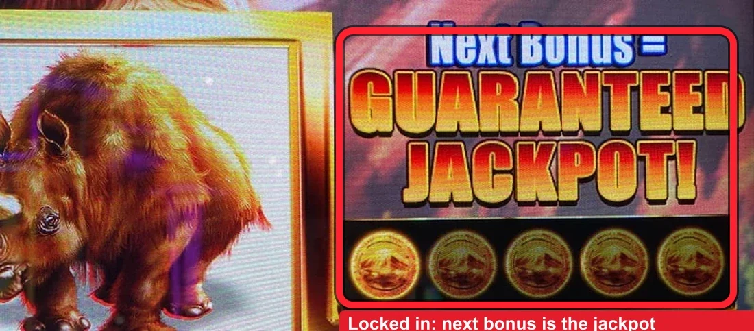 The play state, ringed in red above the fifth reel: the panel has flipped from a coin count to 'Next Bonus = ... JACKPOT!' — one coin left, so the next Volcano Bonus pick is locked in. This is what you are shopping the floor for.