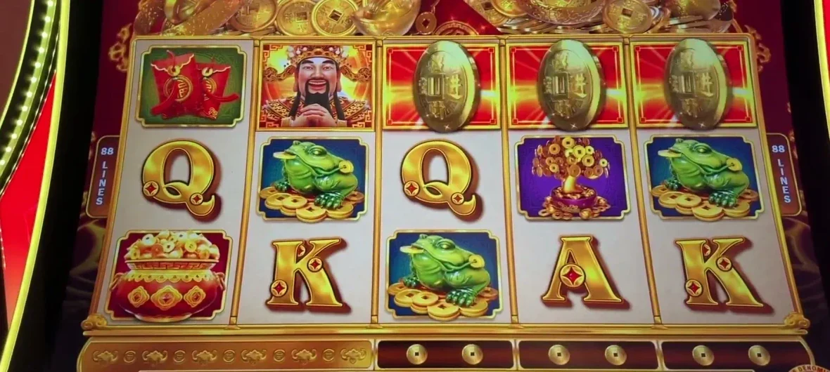Look at the gold coin holders directly below reels three, four and five — the row of trays under the reels. Each coin sitting in a holder counts toward turning that reel wild. Reel three is the one that matters most: two coins below it (or one coin plus a red banner over the reel above) means reel three is wild for the next two spins.